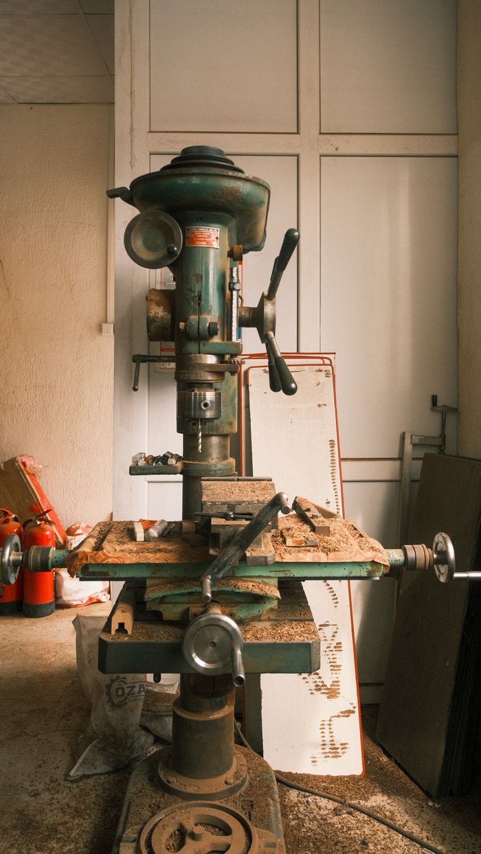 A vintage drill machine used for precision metalwork in an industrial workshop.